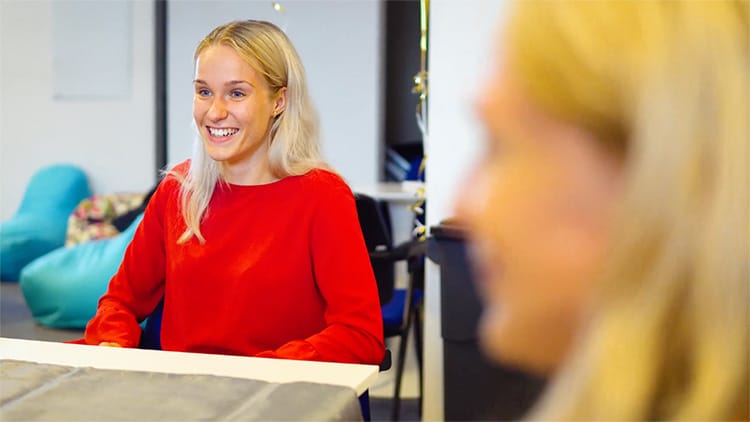 Poistná matematička sa usmieva za stolom v kancelárii